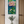 Painting of a water lily on a wall above a small table with a vase of flowers.