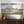 Large painting of a seascape with a person walking on water towards boat, displayed above a wooden console table.