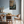 Dining room with wooden table and chairs, light blue walls, and a painting of fish and bread.