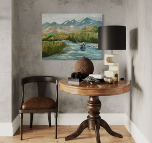 Room interior with a wooden table, chair, lamp, and painting of a mountain landscape.