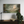 Framed artwork of a religious scene with figures and a cross on a wall above a wooden console table.
