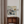 Decorative interior scene with a painting, lamp, and wooden cabinet against a light wall.