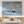 Dining room with a large painting of a boat on the water, placed above a table.